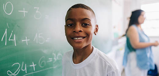 student in front of chalkboard with adult in background