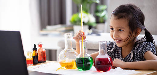 student with three beakers and laptop