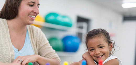 student working with blocks next to adult