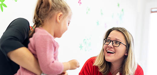 adult holding child while working with another adult